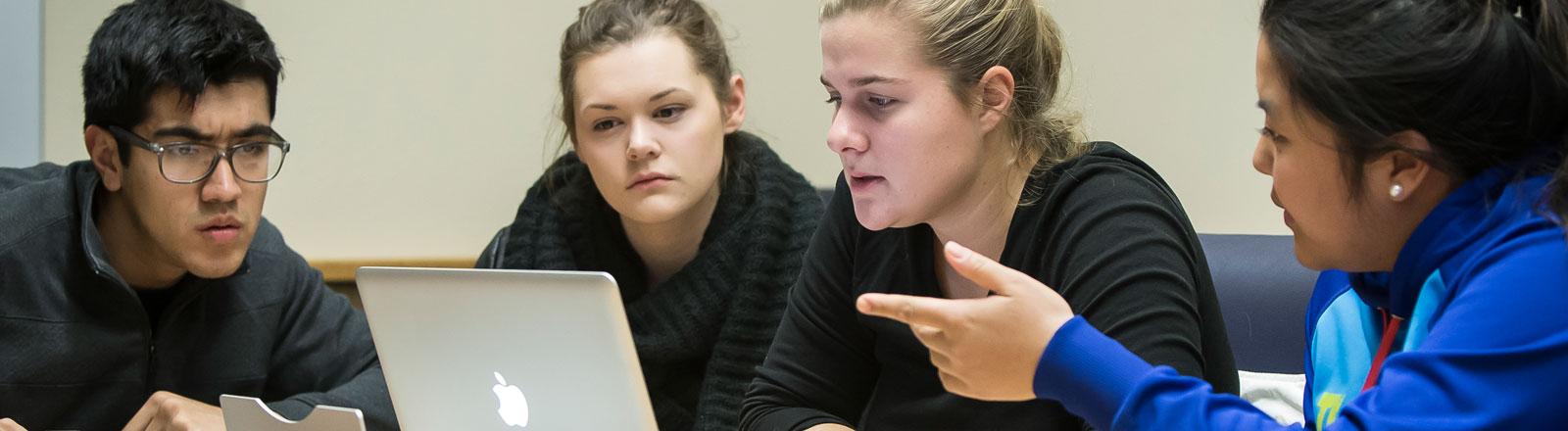 Students gathered at table looking at laptop